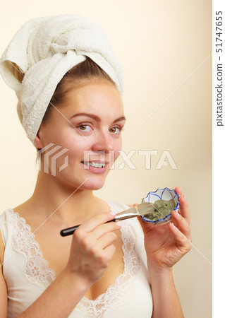 Woman applying with brush clay mud mask to her 51747655