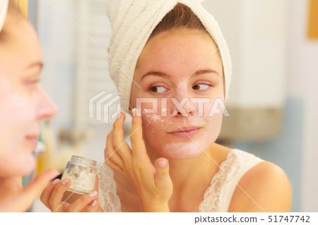 Woman applying mask cream on face in bathroom Woman applying mask cream on face in bathroom 51747742
