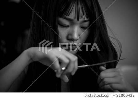 A woman who cuts her hair while crying A woman who cuts her hair while crying 51800422