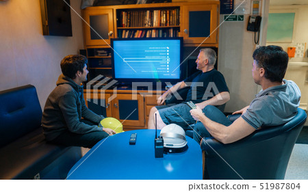 Happy team of ship officers watch TV onboard of vessel 51987804