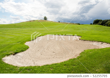 Golf course in early summer A large bunker beside the green with yellow flag Golf course in early summer A large bunker beside the green with yellow flag 52255705