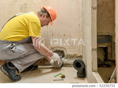 The worker is putting a sewage drain pipe 52256755