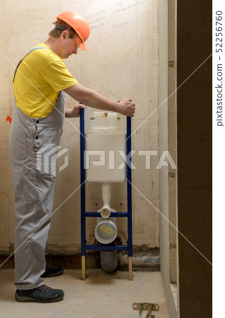 The worker is mounting a built-in toilet tank. 52256760