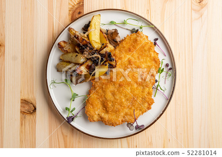 Tasty schnitzel in breading with fried potato 52281014