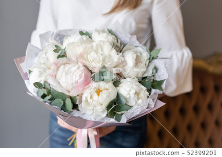 White peonies with eucalyptus in womans hand. Beautiful peony flower for catalog or online store White peonies with eucalyptus in womans hand. Beautiful peony flower for catalog or online store 52399201