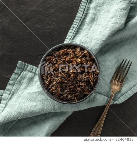 A square photo of wild black rice, shot from the top on a black background with a fork and copy A square photo of wild black rice, shot from the top on a black background with a fork and copy 52404032