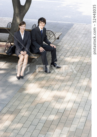 Men and women in suits sitting in the shade of trees 52448035