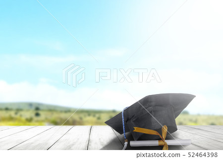 Mortarboard hat and diploma on wooden table 52464398