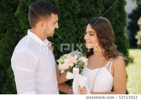 Handsome man and beautiful girl in white clothes. Couple walking outside. Bouquet of flowers Handsome man and beautiful girl in white clothes. Couple walking outside. Bouquet of flowers 52513022