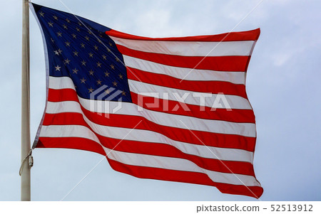 United States flag blows in the wind against a sky United States flag blows in the wind against a sky 52513912