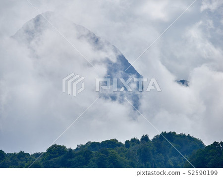 High mountain with green slopes hidden in clouds High mountain with green slopes hidden in clouds 52590199