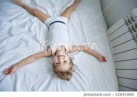 Happy kids playing in white bedroom. Little boy and girl, brother and sister play on the bed wearing Happy kids playing in white bedroom. Little boy and girl, brother and sister play on the bed wearing 52691860