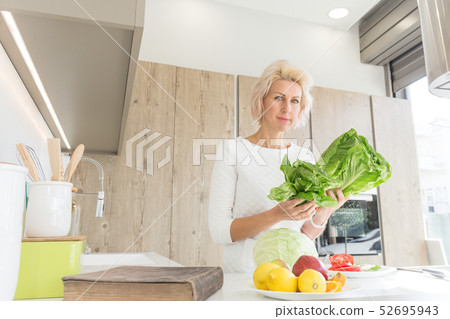 young blonde woman cooking in modern kitchen young blonde woman cooking in modern kitchen 52695943