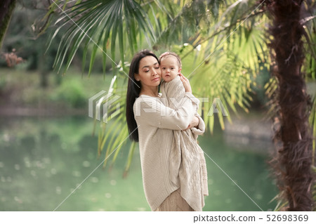 Young and happy mother cares for her young son, and walks along the shore of the lake in the summer Young and happy mother cares for her young son, and walks along the shore of the lake in the summer 52698369