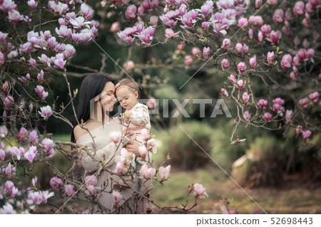 Young mother and little daughter in autumn park play with magnolia leaves. Happy weekend with family Young mother and little daughter in autumn park play with magnolia leaves. Happy weekend with family 52698443
