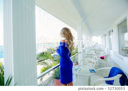 Blonde girl looks through window 52730053