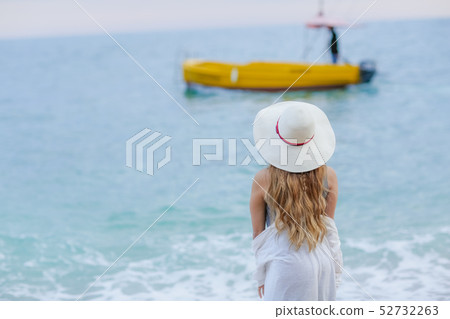 Adorable wedding couple holds each other hands walking along the beach against the rocks and ocean Adorable wedding couple holds each other hands walking along the beach against the rocks and ocean 52732263