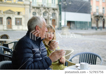 Two middle-aged tourists drinking coffee in cafe with terrace outdoors in the ancient city in the Two middle-aged tourists drinking coffee in cafe with terrace outdoors in the ancient city in the 52765756