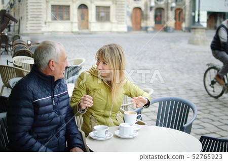 Portrait of happy romantic couple with age difference drinking coffee in cafe with terrace outdoors Portrait of happy romantic couple with age difference drinking coffee in cafe with terrace outdoors 52765923