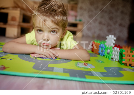 Adorable gingerish little boy laying on floor, playing with building cubes 52801169