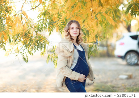 Beautiful pregnant woman stands next to the sunset Beautiful pregnant woman stands next to the sunset 52805171