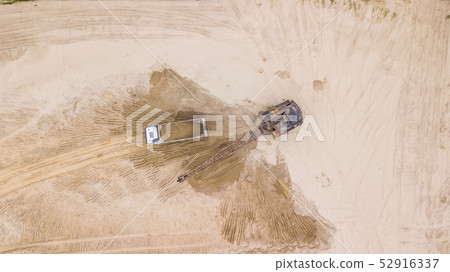 Tod down view of excavator pours sand into the truck. On the construction site. Tod down view of excavator pours sand into the truck. On the construction site. 52916337