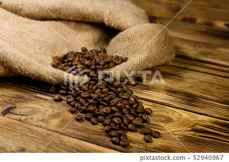 Roasted coffee beans on sackcloth on wooden table Roasted coffee beans on sackcloth on wooden table 52940967