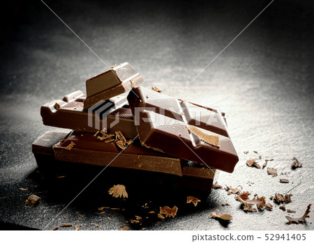 Cracked dark chocolate bar at black background 52941405