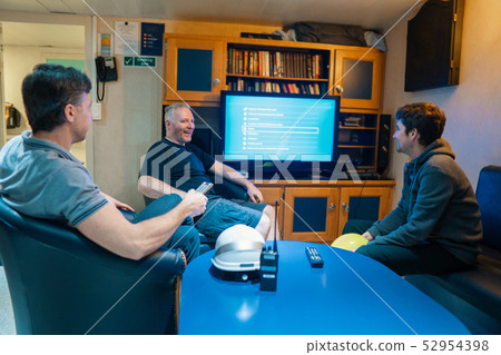 Happy team of ship officers watch TV onboard of vessel 52954398