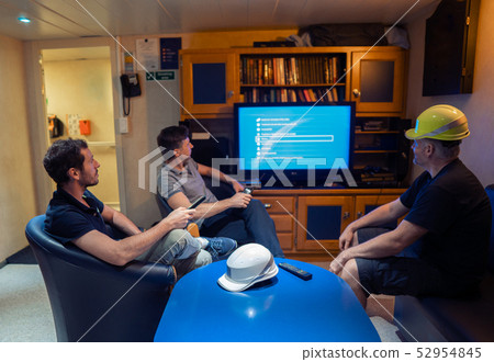 Happy team of ship officers watch TV onboard of vessel Happy team of ship officers watch TV onboard of vessel 52954845