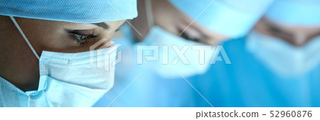 Three surgeons at work operating in surgical theatre Three surgeons at work operating in surgical theatre 52960876