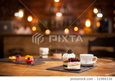 Composition of different cakes with tasty flavours over a wooden table in a coffee shop 52966336