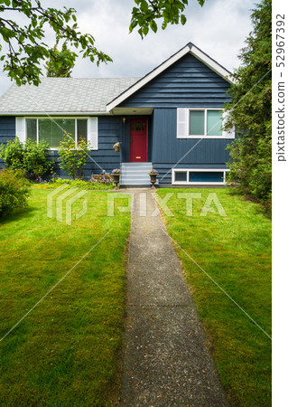 Small family house with green lawn and decorative flowers at the door 52967392