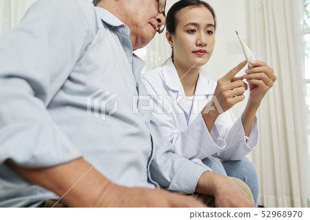 Nurse measuring the temperature of senior man 52968970