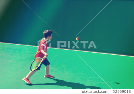Little tennis player on a blurred green background Little tennis player on a blurred green background 52969018