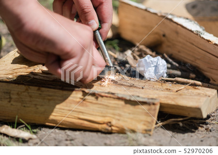 A pair of hands making a fire with flint and steel 52970206