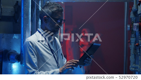 Scientist checking equipment and using tablet 52970720