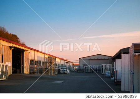 A logistics warehouse with steel water piling up in the evening glow 52980859
