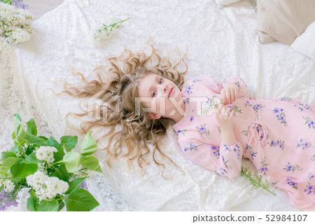 little girl with blond hair with lilac flowers 52984107