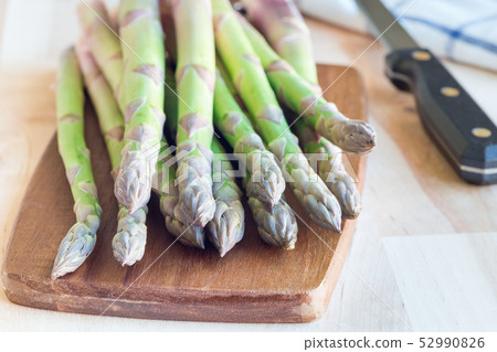 Bunch of fresh green asparagus on wooden board 52990826