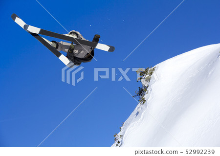 Extreme skier jumping from mountain blue sky in Extreme skier jumping from mountain blue sky in 52992239