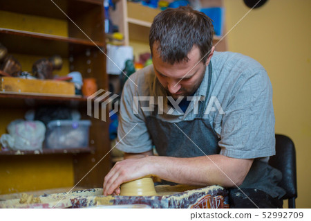 Professional male potter working with clay on potter's wheel 52992709