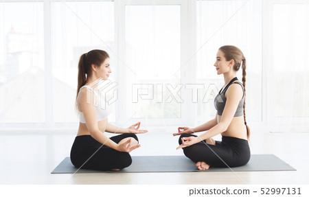 Young women concentrating in Lotus pose in front of each other Young women concentrating in Lotus pose in front of each other 52997131
