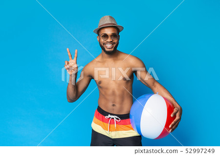 Shirtless black guy holding inflatable ball, showing v sign 52997249