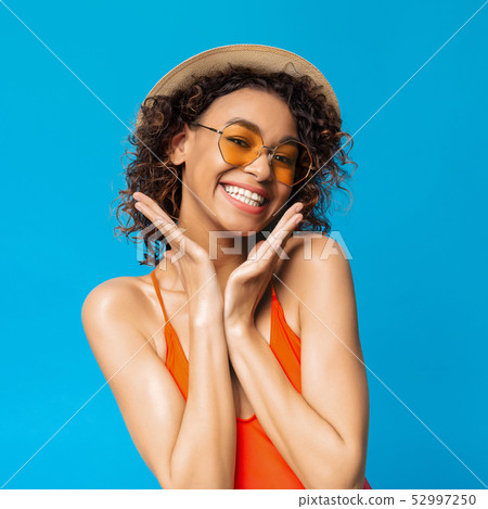 Black girl in swimwear and sunglasses laughing on blue Black girl in swimwear and sunglasses laughing on blue 52997250