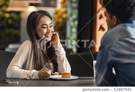 African american teenage girl flirting with boyfriend in cafe African american teenage girl flirting with boyfriend in cafe 52997441