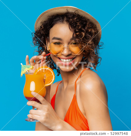 Carefree black girl enjoying fruit non-alcoholic cocktail Carefree black girl enjoying fruit non-alcoholic cocktail 52997548
