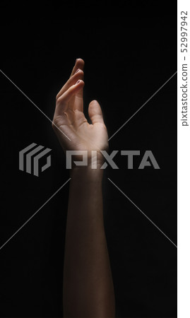 Naked female hand reaching to light on black Naked female hand reaching to light on black 52997942