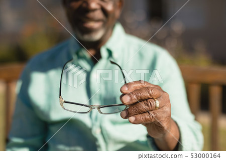 Senior man holding spectacle in the park of nursing home  53000164