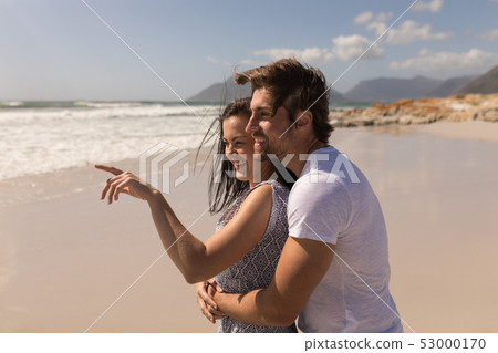 Side view of romantic happy young couple embracing on beach 53000170